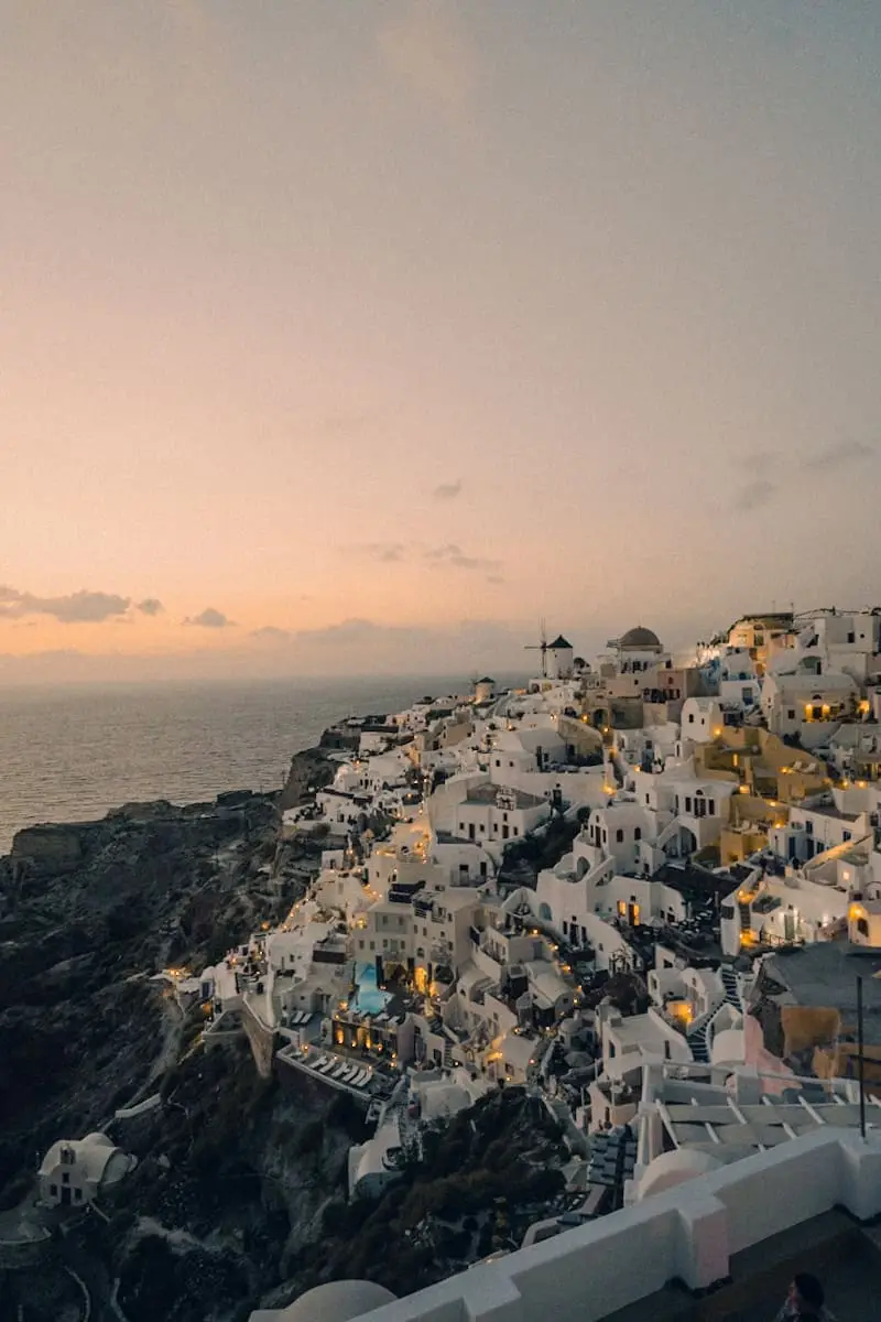 (2026) Postcard From Oia Apricot and pink sunset light over the white rooftops of Oia, Santorini
