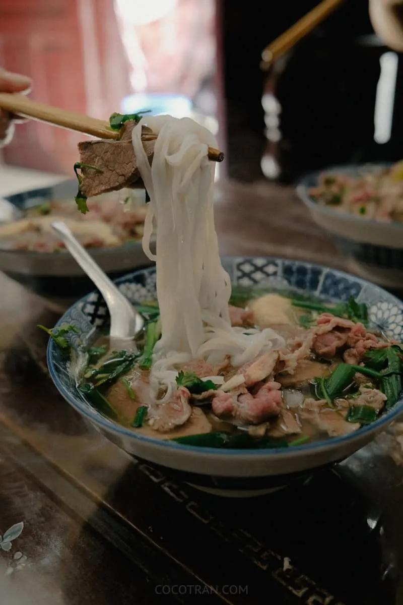 Lifting rice noodles from a bowl of pho in Hanoi, Vietnam